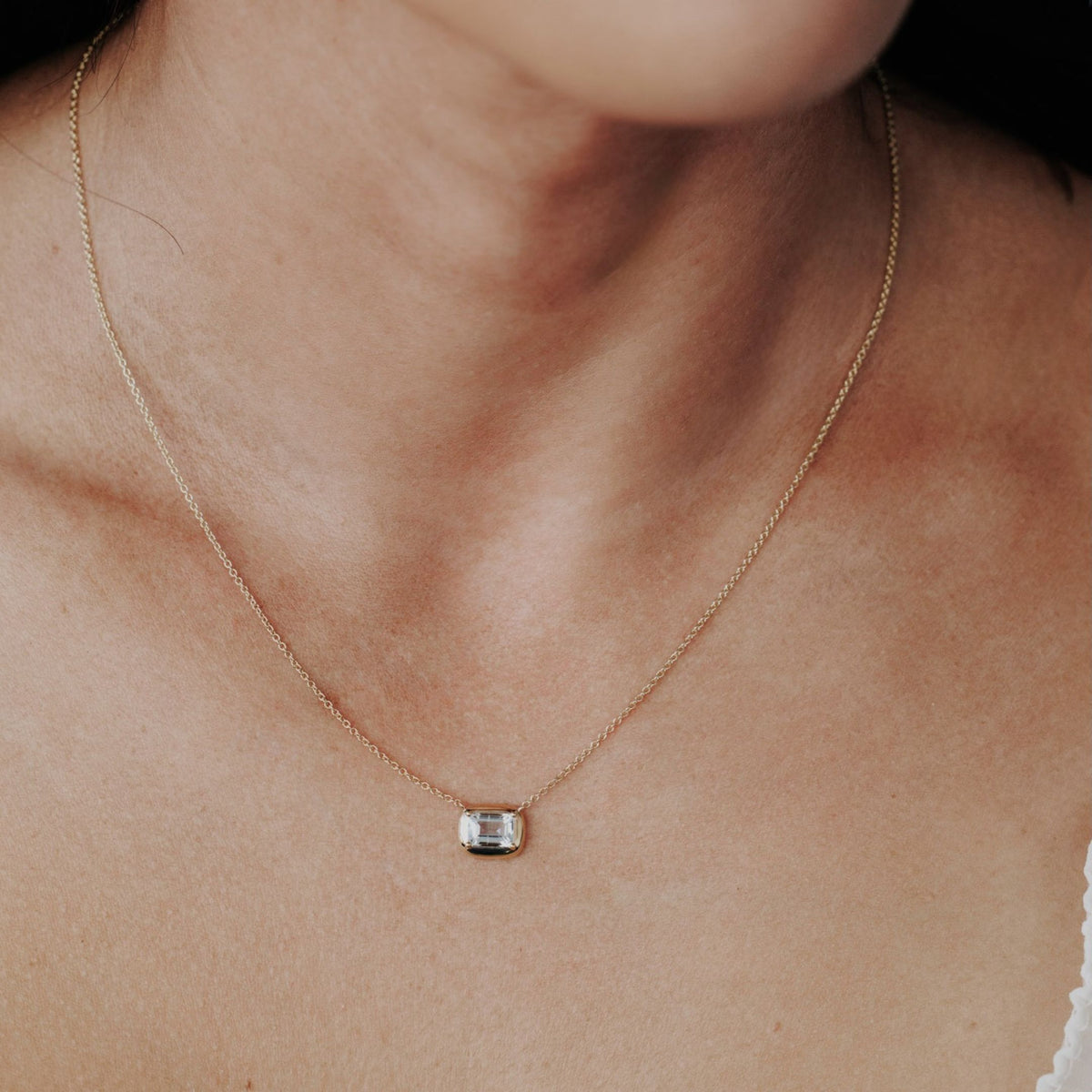 An emerald cut aquamarine necklace placed on the neck of a model.