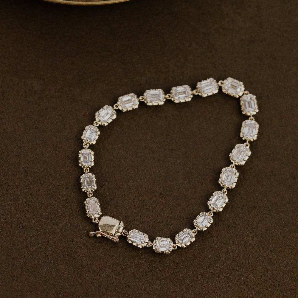 Diamond tennis bracelet with emerald cut lab grown diamonds on a brown background.