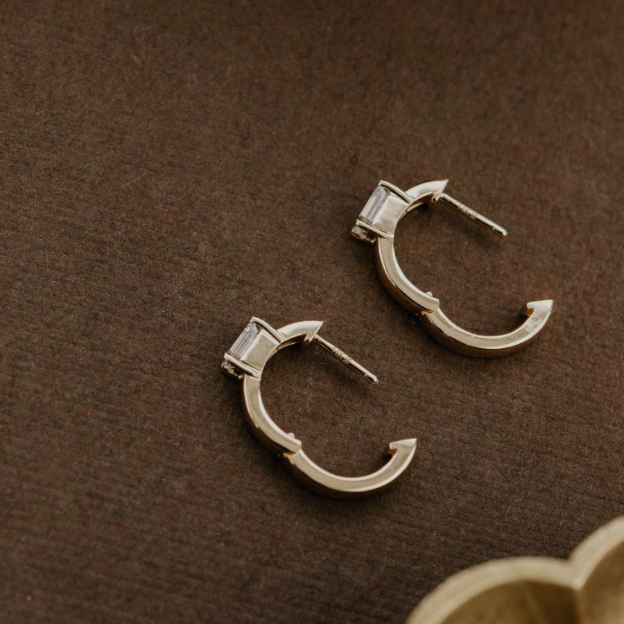 Pair of yellow gold hoop earrings on a brown surface.