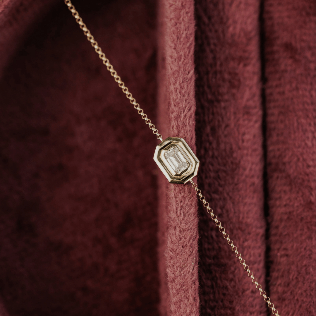 14k gold emerald cut, lab grown diamond chain bracelet showcased in a red jewelry case. 