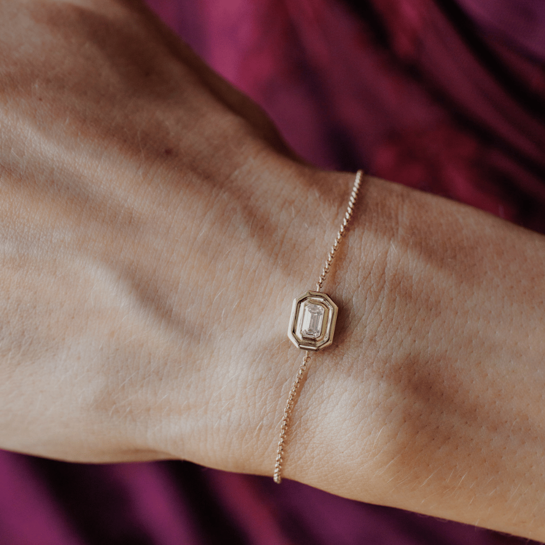 14k gold emerald cut, lab grown diamond chain bracelet showcased on the wrist of a model. 