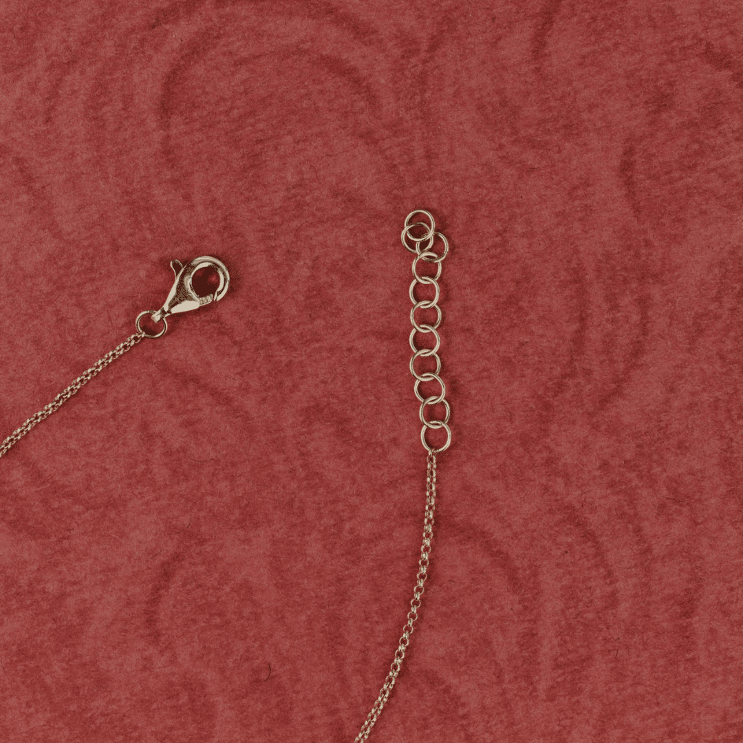 14k gold emerald cut, lab grown diamond chain bracelet showcased on a textured red surface. Showing the clasp of the bracelet. 