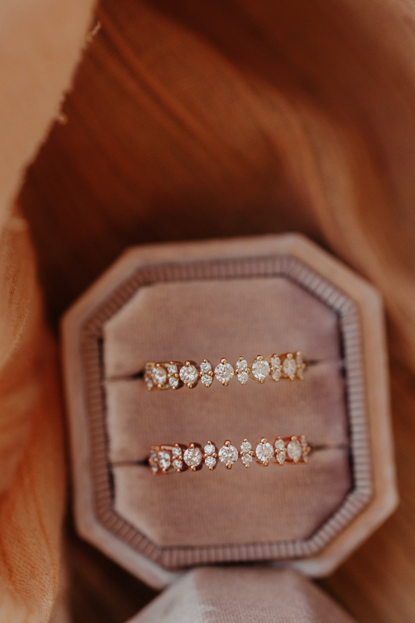 Two round diamond wedding bands in 14k yellow and rose gold in a pink velvet ring box.
