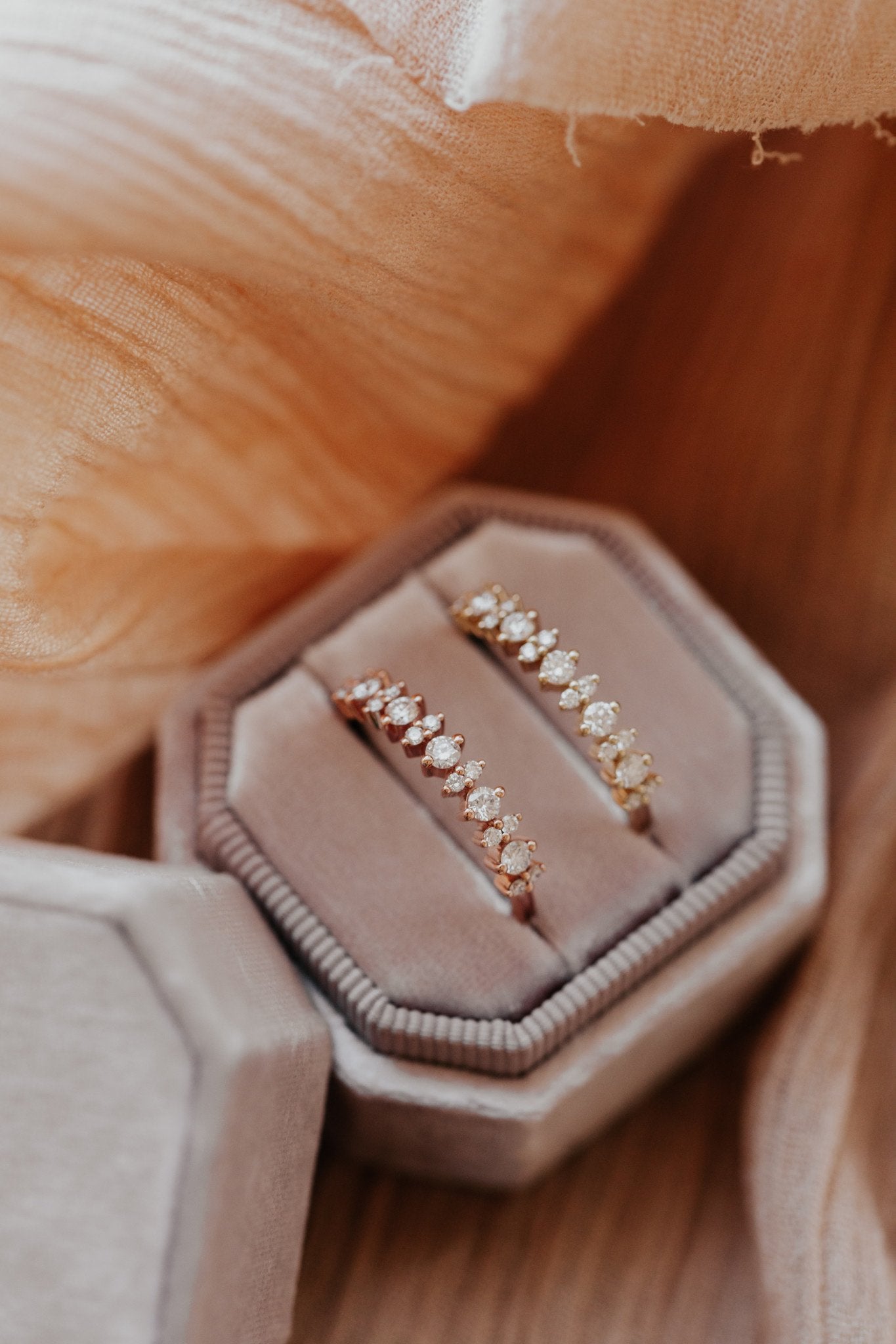 Two round diamond wedding bands in 14k yellow and rose gold in a velvet ring box.