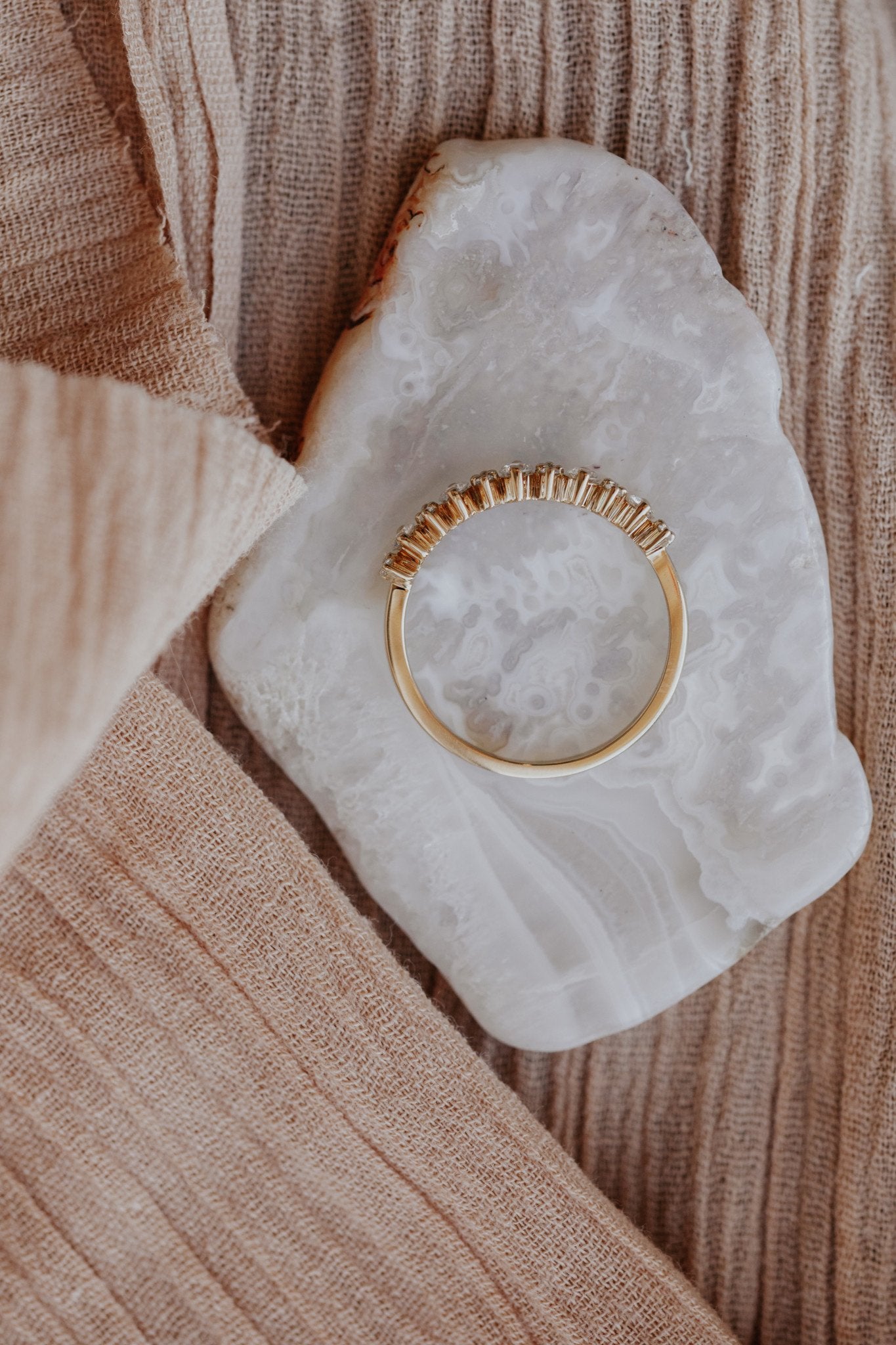 Top-down shot of a 14k yellow gold wedding band on a textured surface.