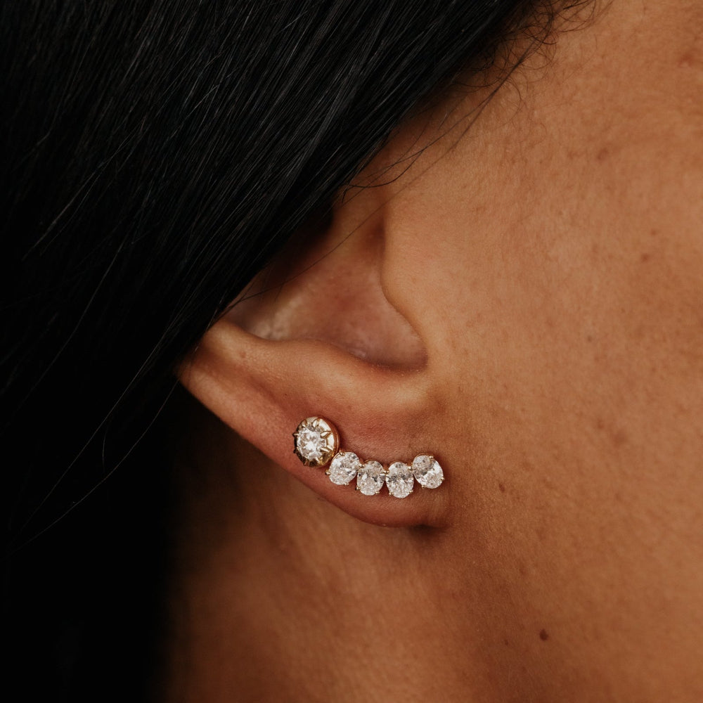 Close-up of an ear wearing lab grown diamond stud earrings with dark hair partially covering the face.