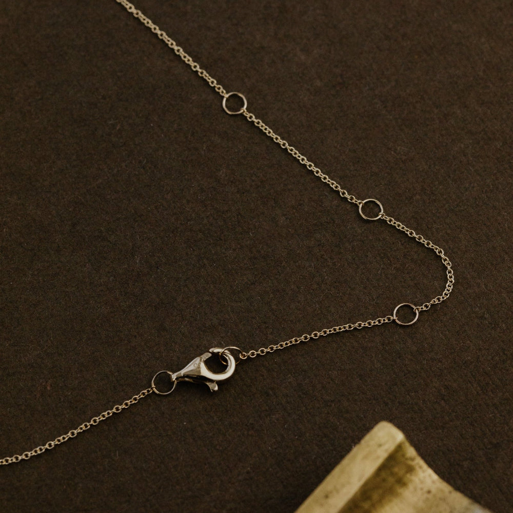 Yellow gold chain necklace on a brown textured background.