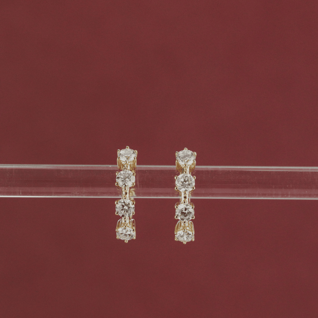 14k gold diamond 4-prong huggie earrings set showcased on a clear tube in the center of the screen. 