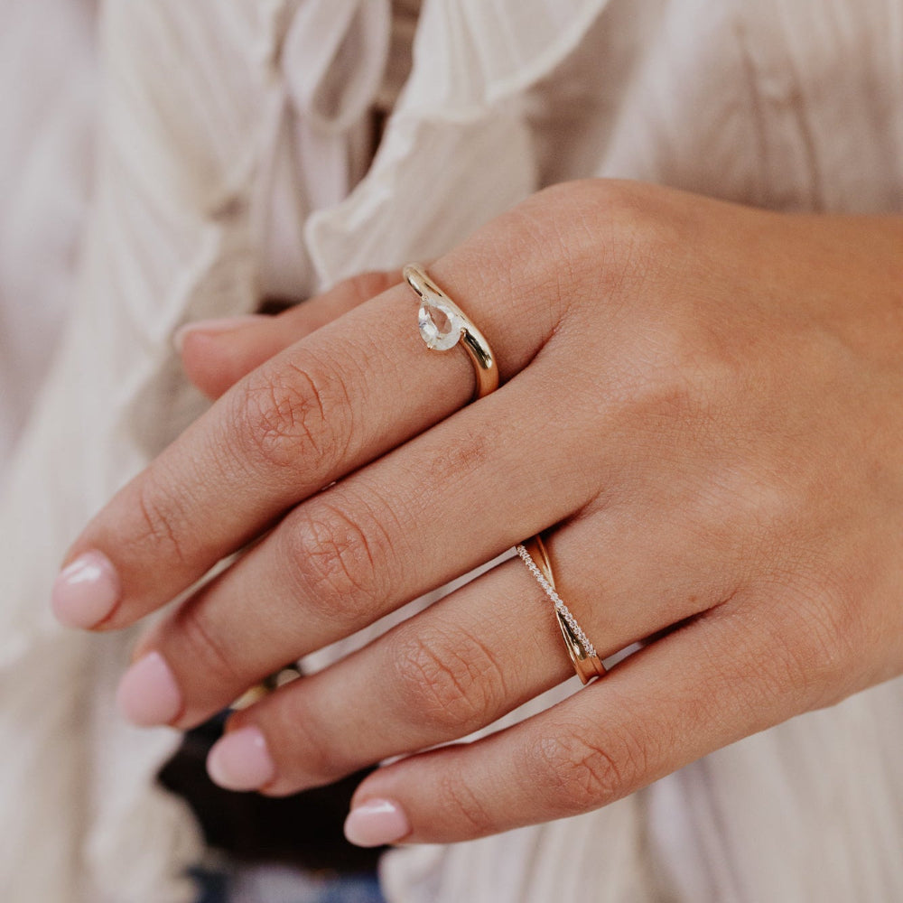 Close-up of a hand wearing multiple gold rings with a blurred background