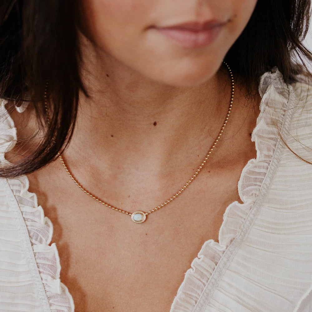 Close-up of a person wearing a delicate gold necklace with a small pendant.