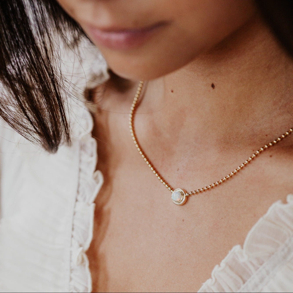 Close-up of a person wearing a delicate gold necklace with a small pendant.