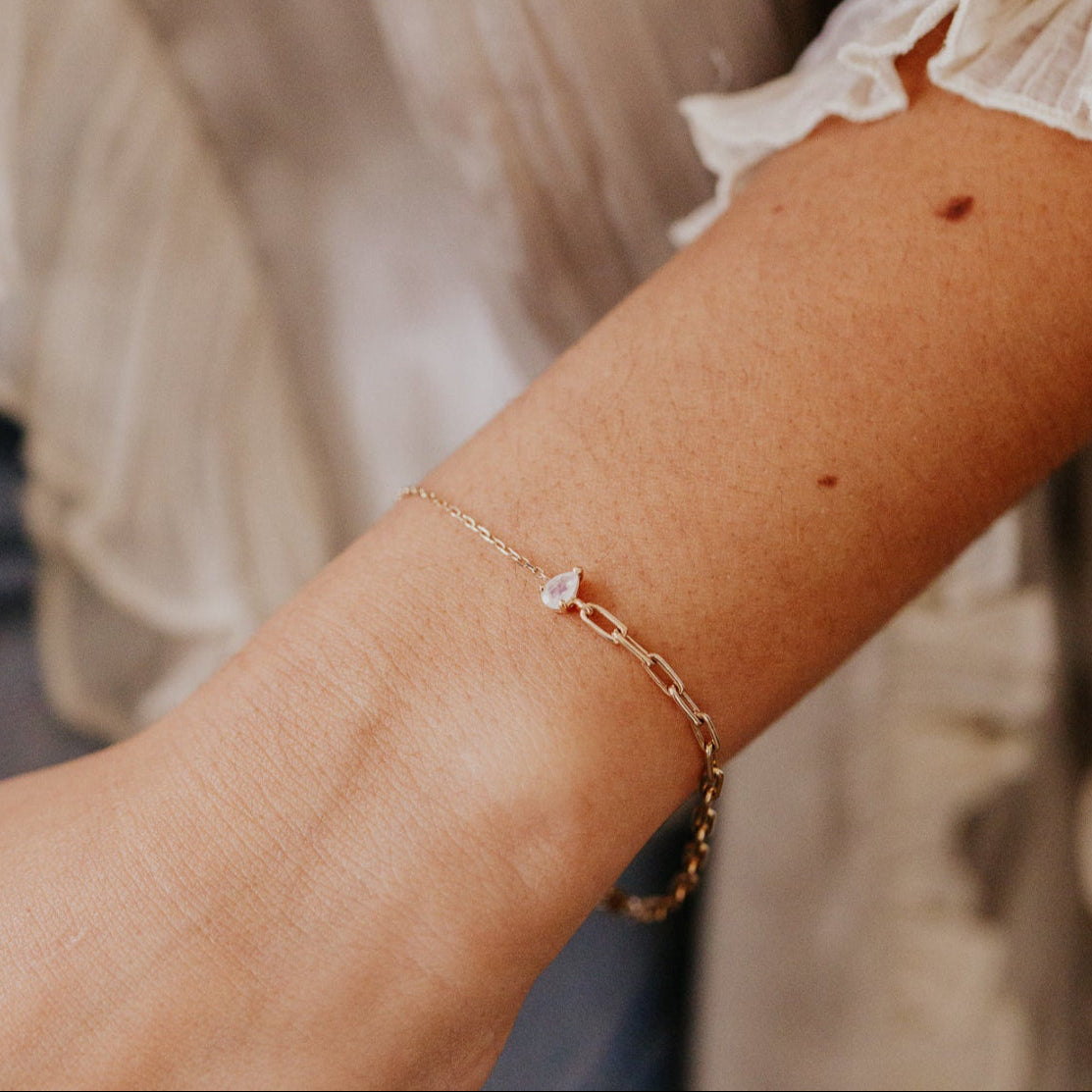 Gold bracelet with a moonstone on a wrist with a blurred background
