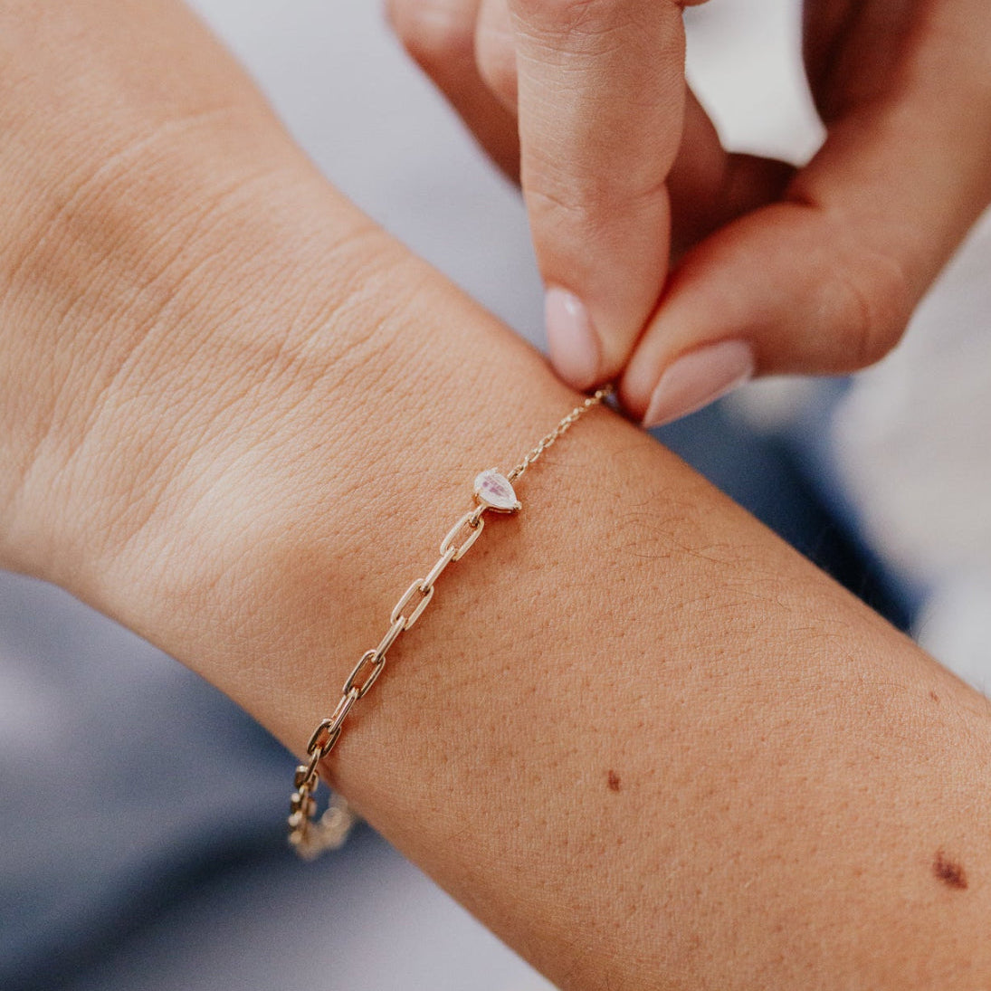 Close-up of a hand wearing a gold bracelet on a blurred background