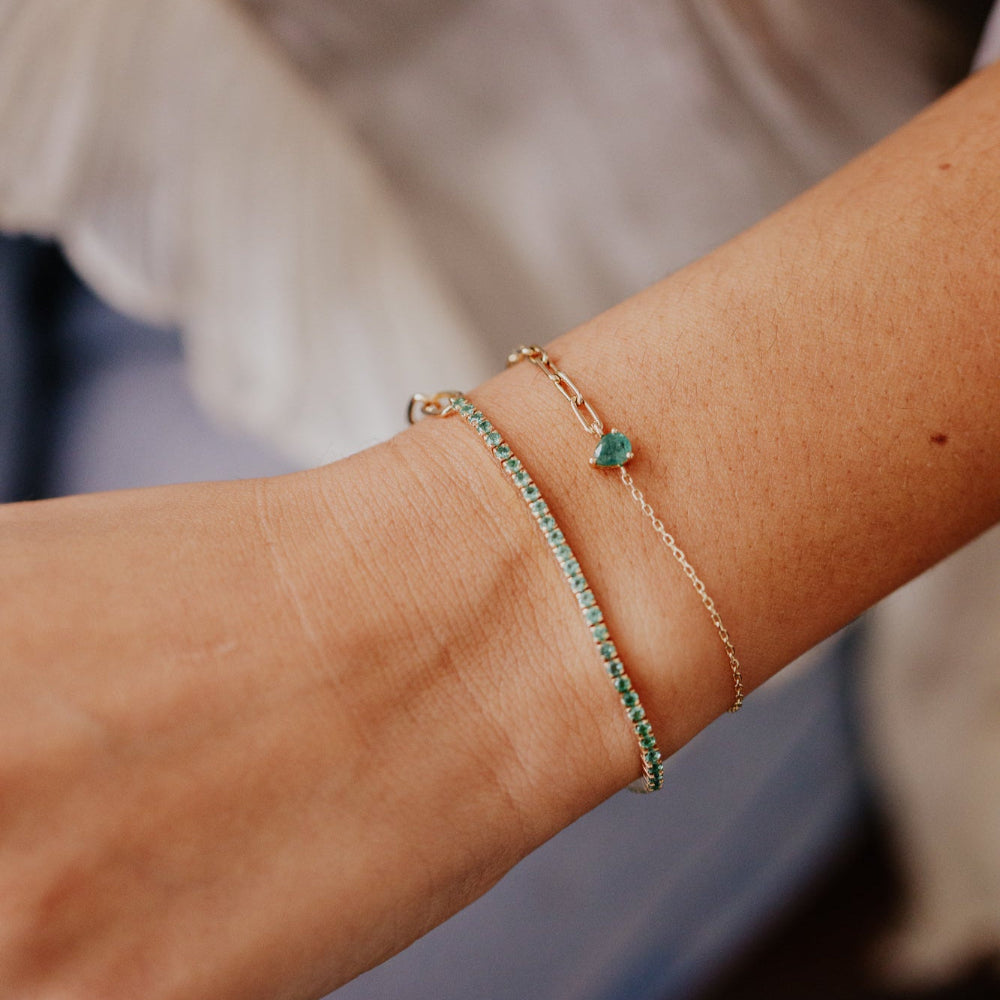 Close-up of a person's wrist wearing two bracelets with green stones.