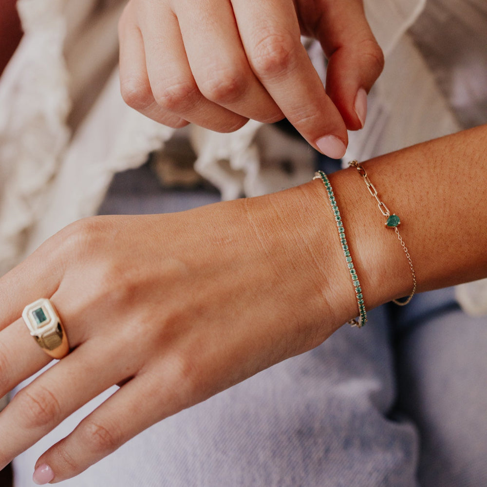 Close-up of a person's hand wearing a ring and bracelet with a blurred background