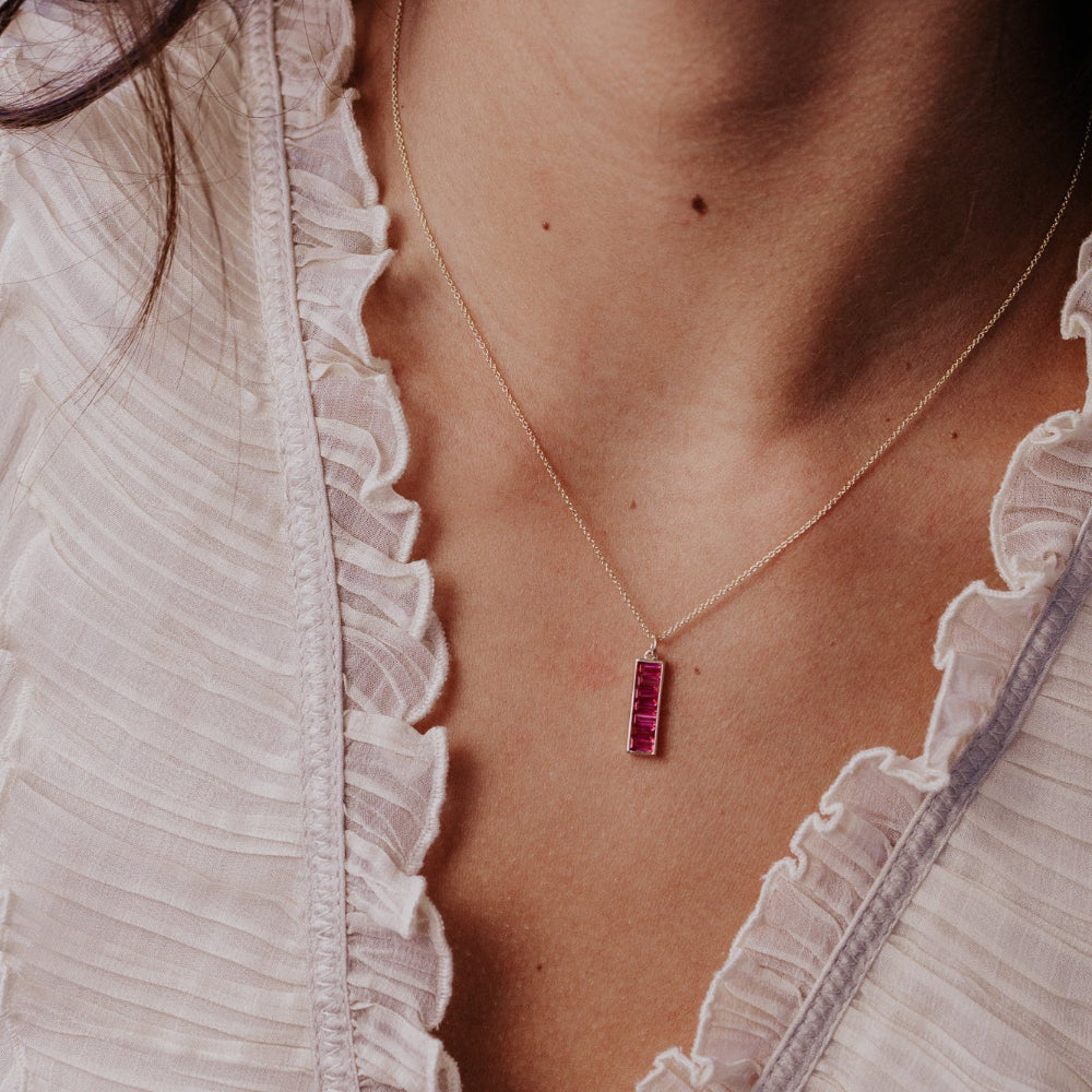 Necklace with a Pink Topaz gemstone pendant worn by a person in a light-colored outfit.
