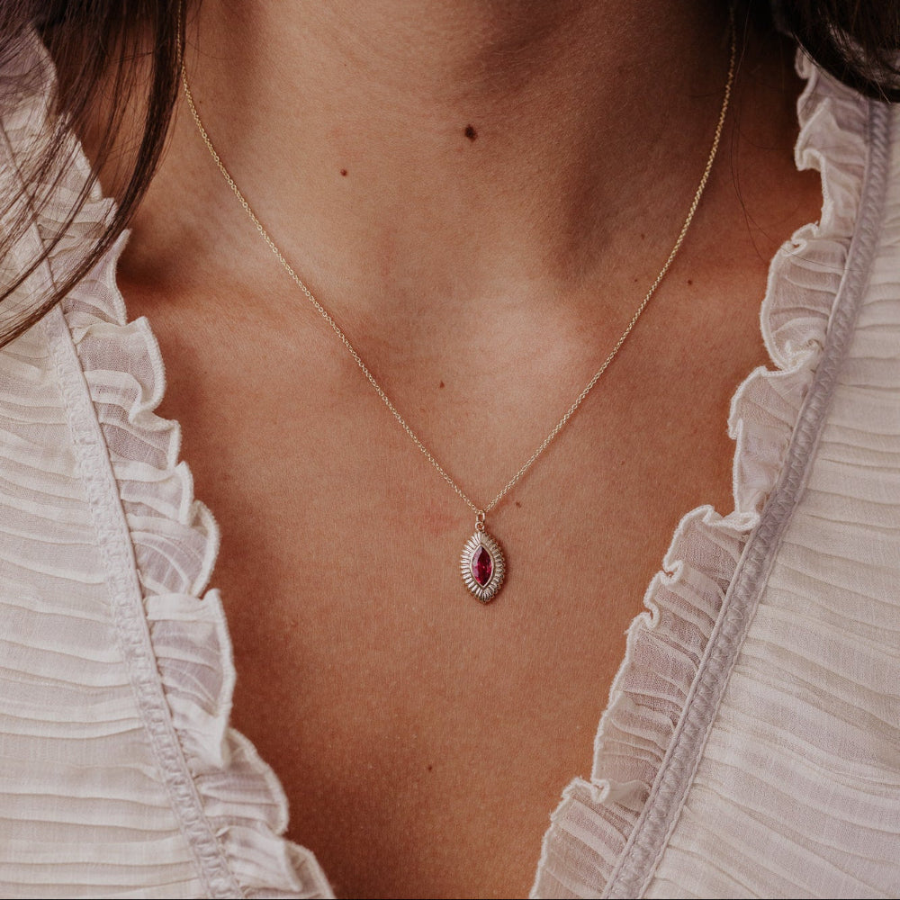Necklace with a pink tourmaline gemstone pendant worn by a person in a white ruffled top.
