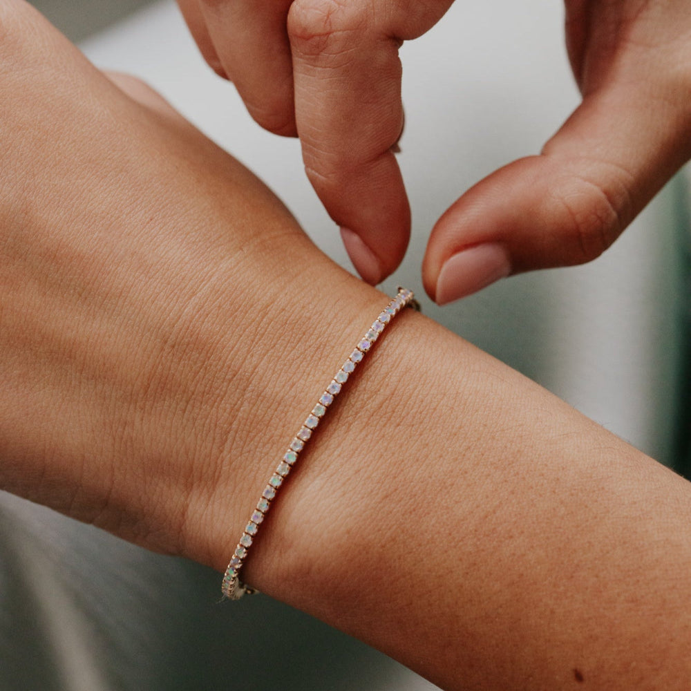 Close-up of a hand wearing a diamond bracelet with another hand adjusting it.