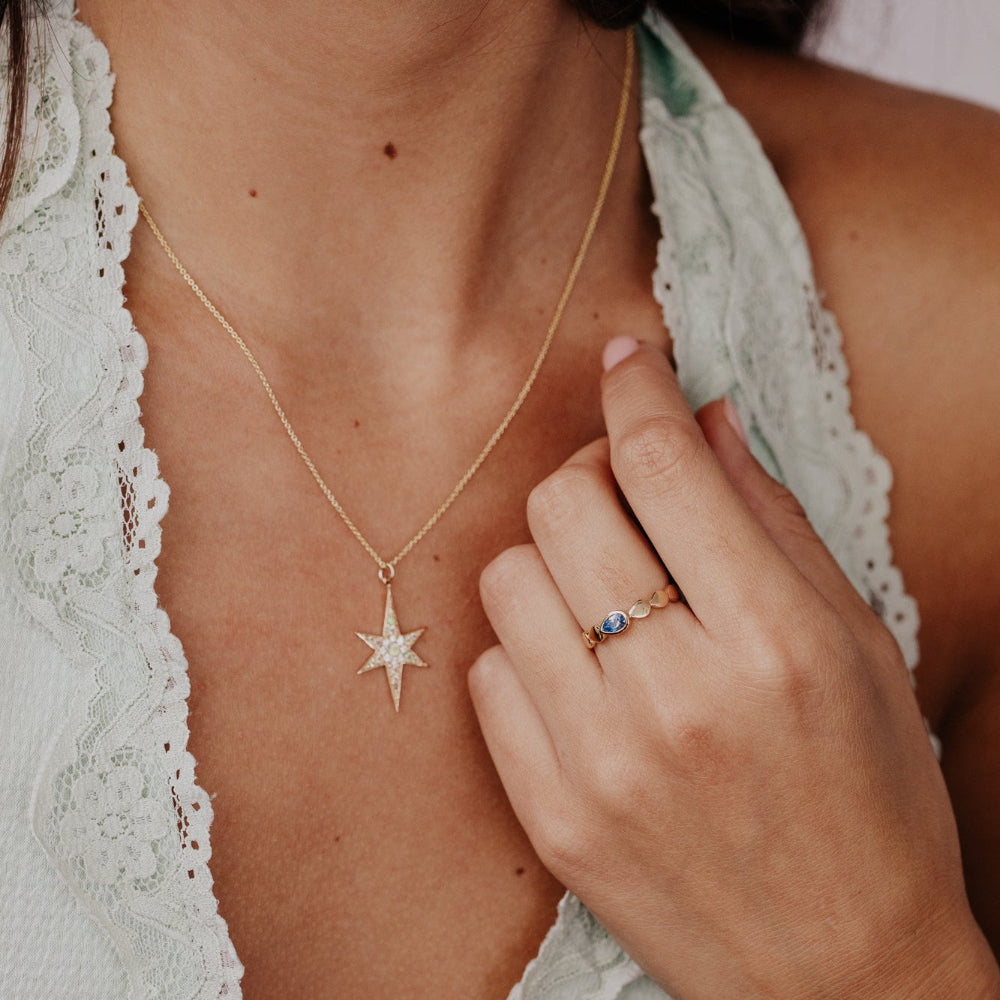 Woman wearing a gold necklace with a star pendant and a ring on her finger.