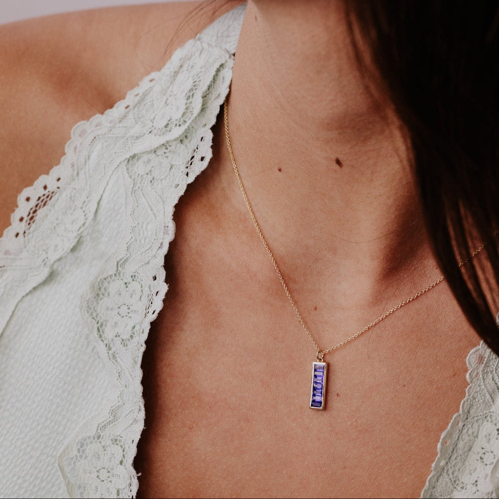 Close-up of a woman wearing a delicate necklace with a Kyanite pendant.