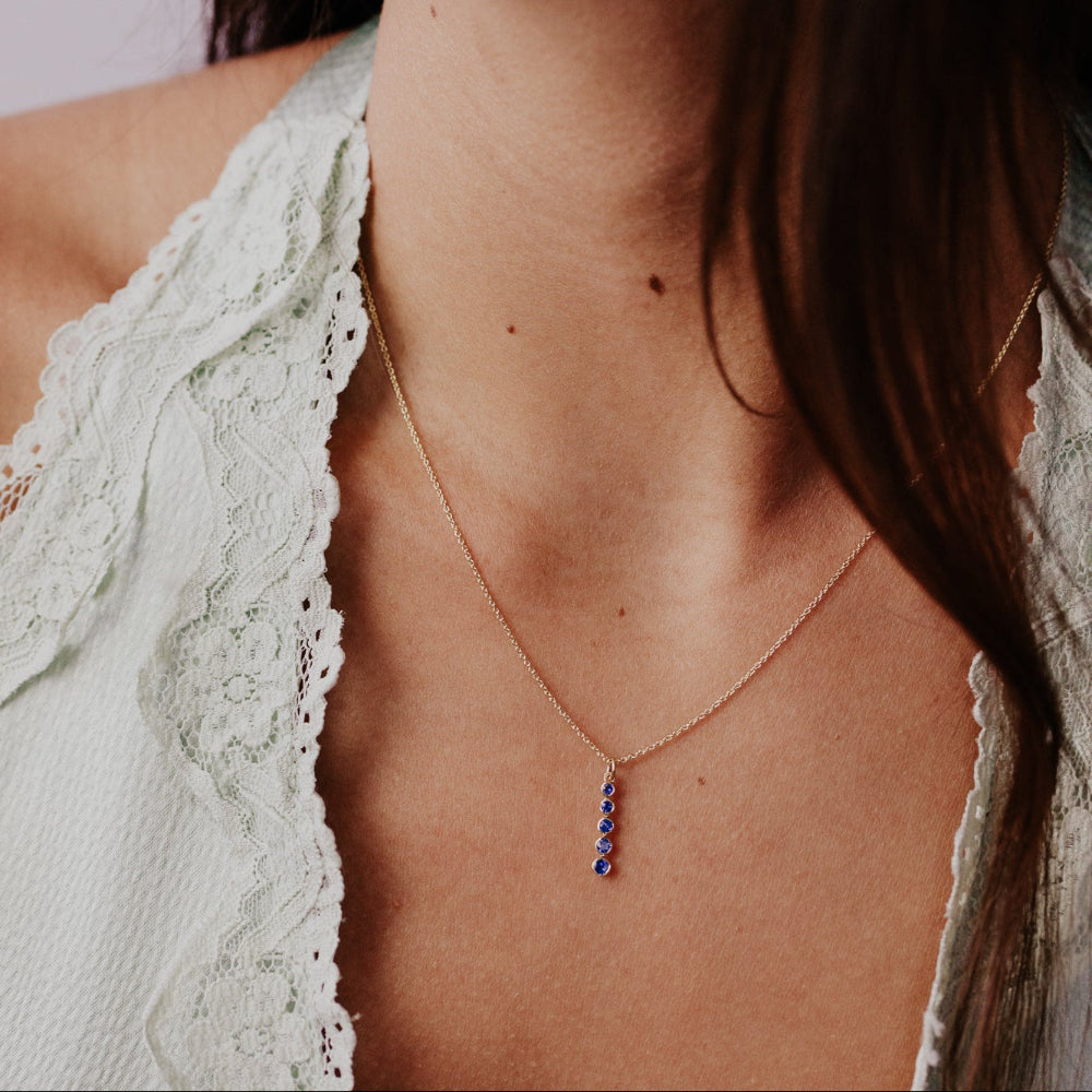 Necklace with blue sapphire stones worn by a person with a light green lace garment.