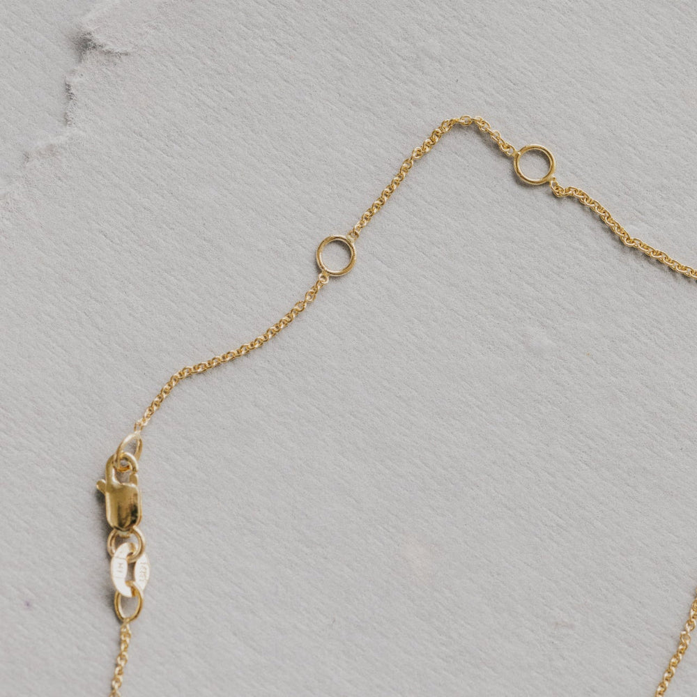 Gold chain necklace on a gray textured background