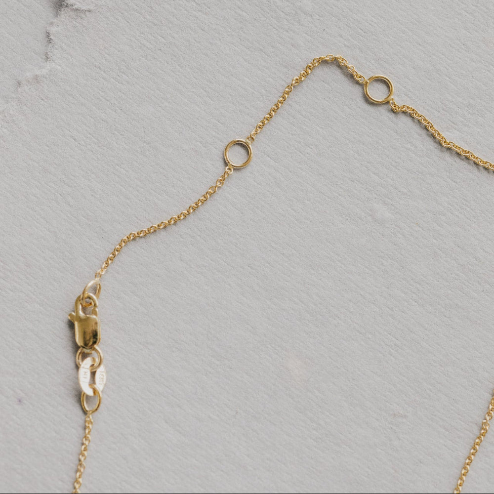 Gold necklace chain on a textured gray surface