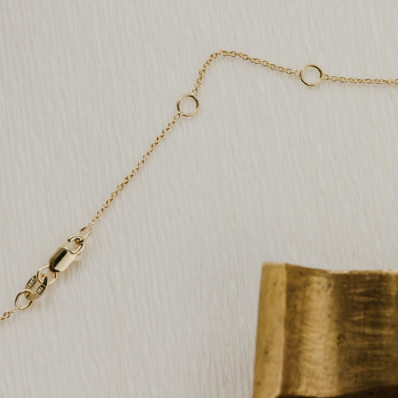 Gold chain necklace on a textured beige background