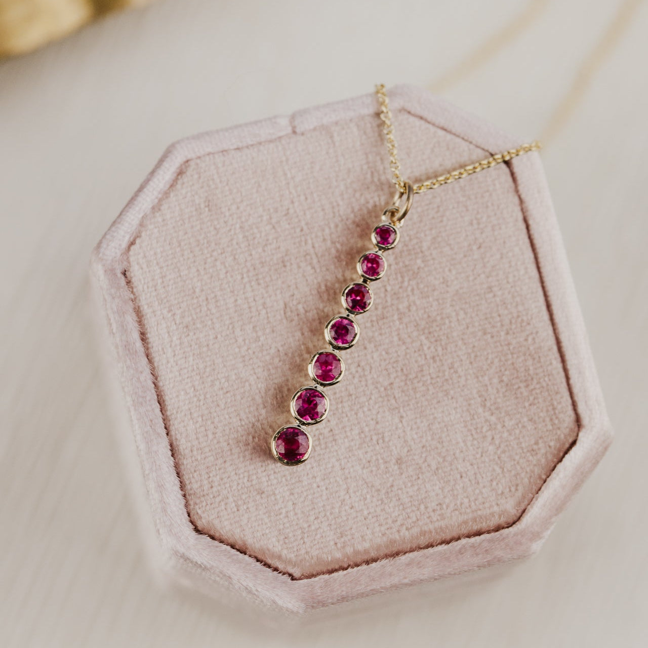 Necklace with red gemstones on a pink jewelry box