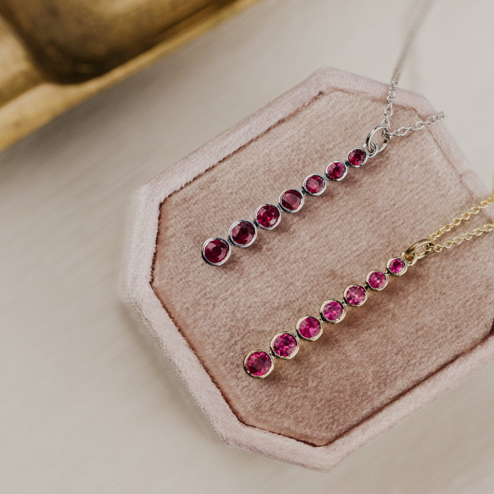 Necklace with red ruby gemstones on a pink stand