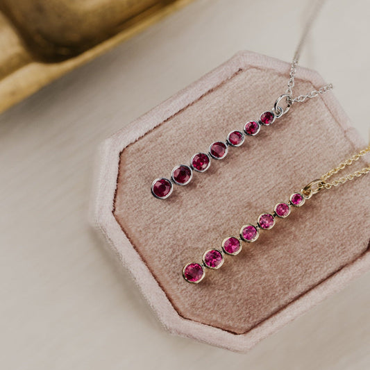 Necklace with red ruby gemstones on a pink stand