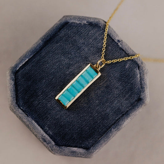Necklace with a turquoise pendant on a blue cushion