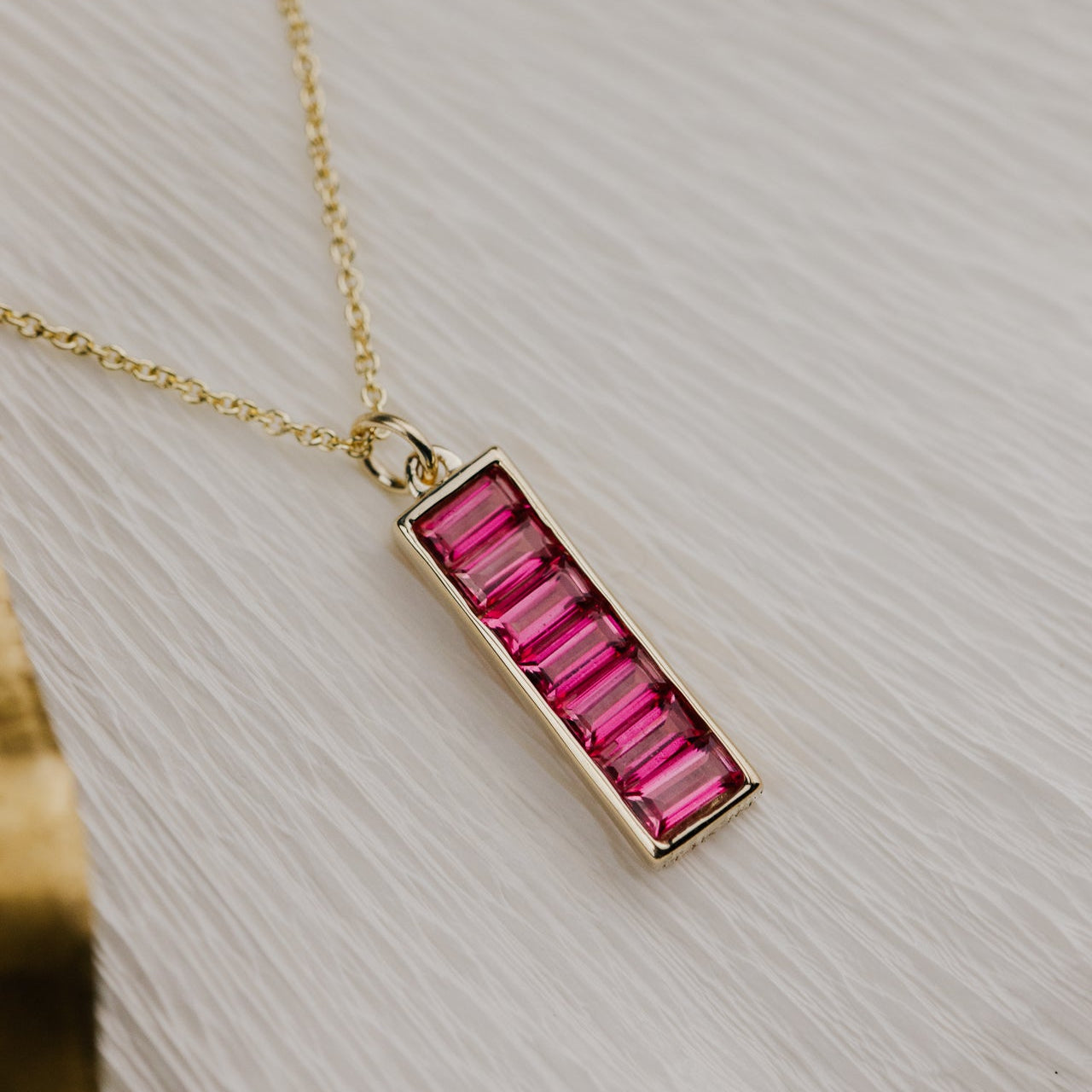 Necklace with a pink Pink Topaz on a textured white surface