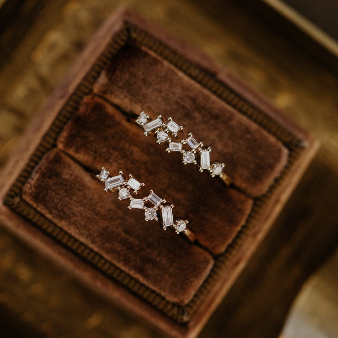 Diamond wedding band on a brown velvet cushion in a jewelry box.