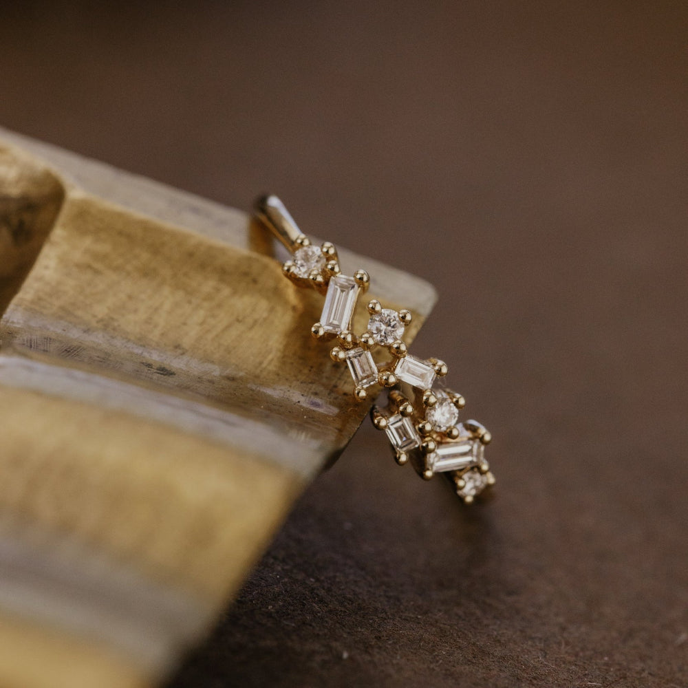 Gold wedding band with diamonds on a brown surface.