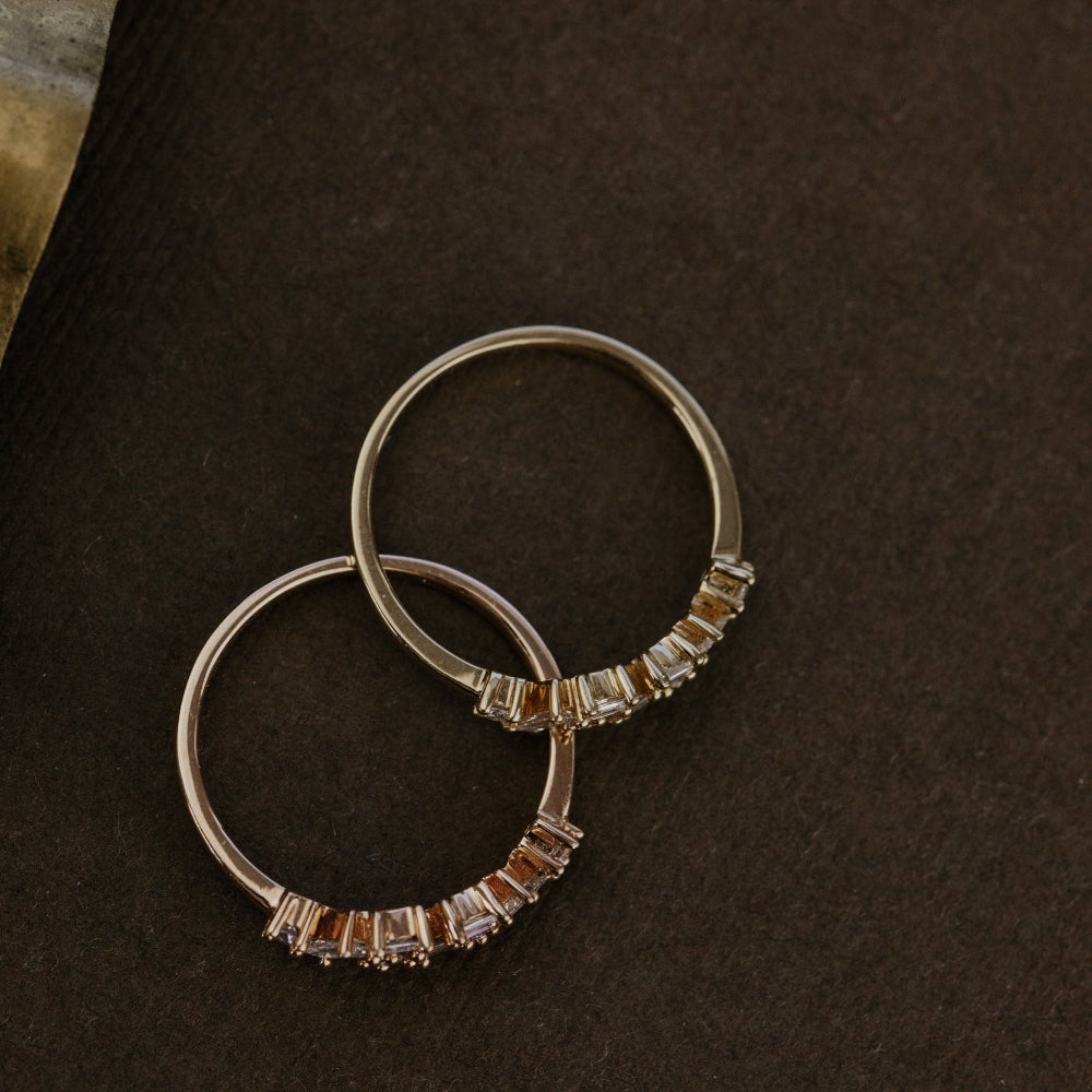 Pair of gold wedding bands on a dark surface.