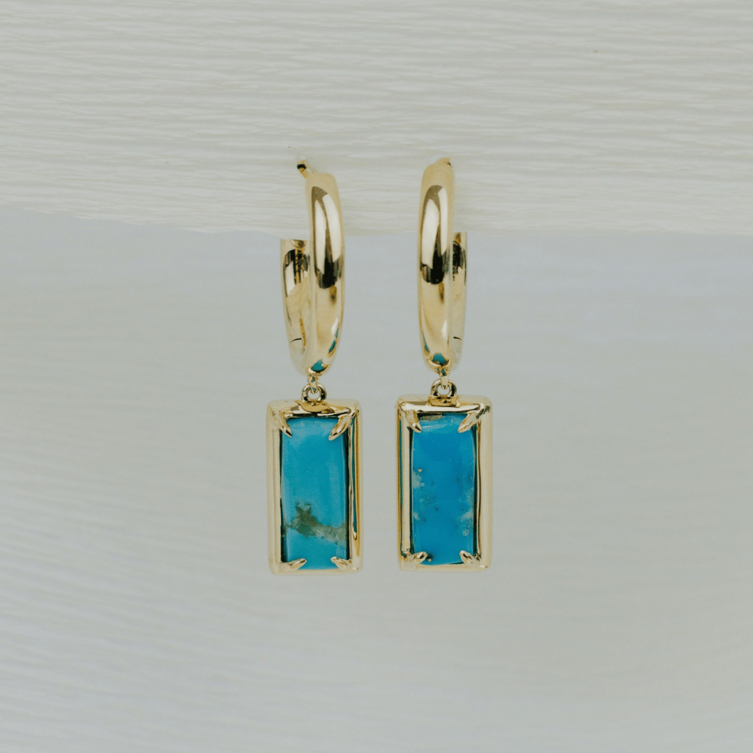 14k gold rectangle turquoise dangle hoop earrings on a textured white background. 