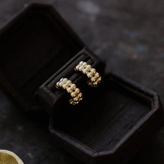 Gold hoop earrings in a black jewelry box on a dark surface