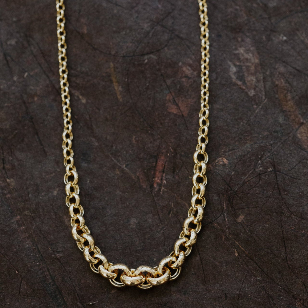 Gold chain necklace on a dark textured surface