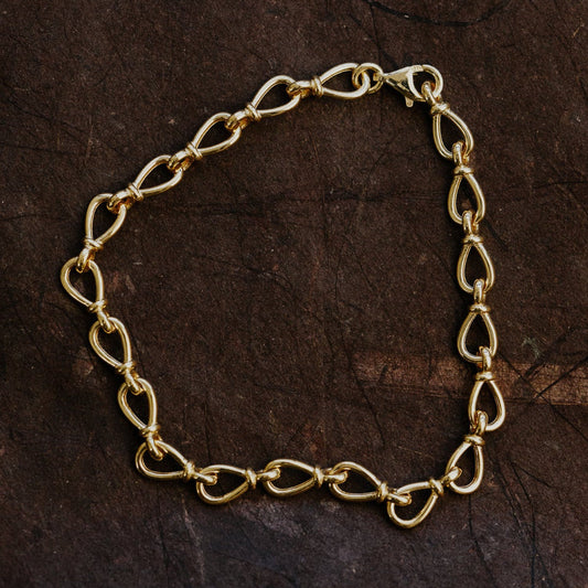 Gold chain bracelet on a dark brown textured surface