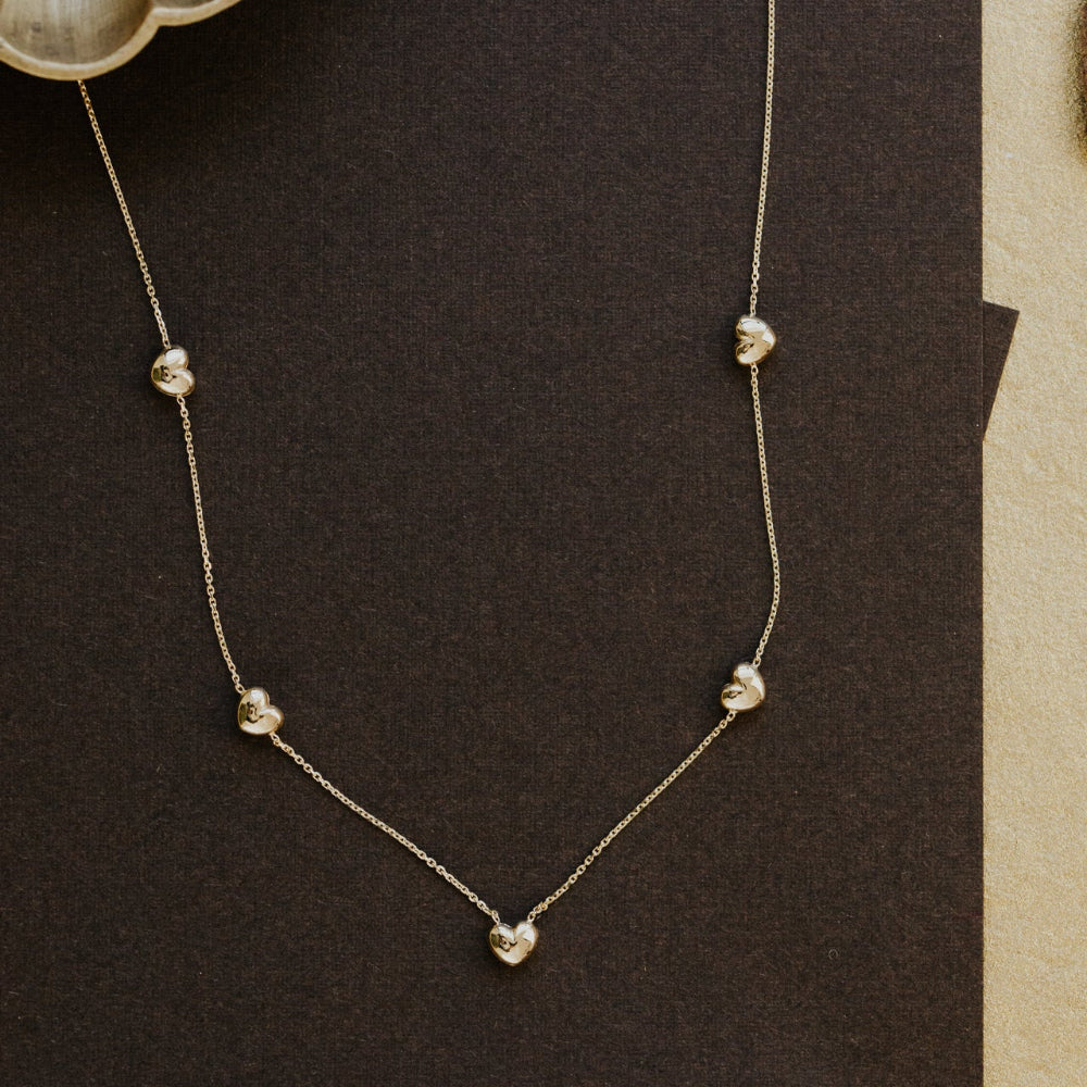 Delicate necklace with small gold hearts on a dark background