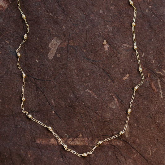 Gold chain necklace on a textured brown surface