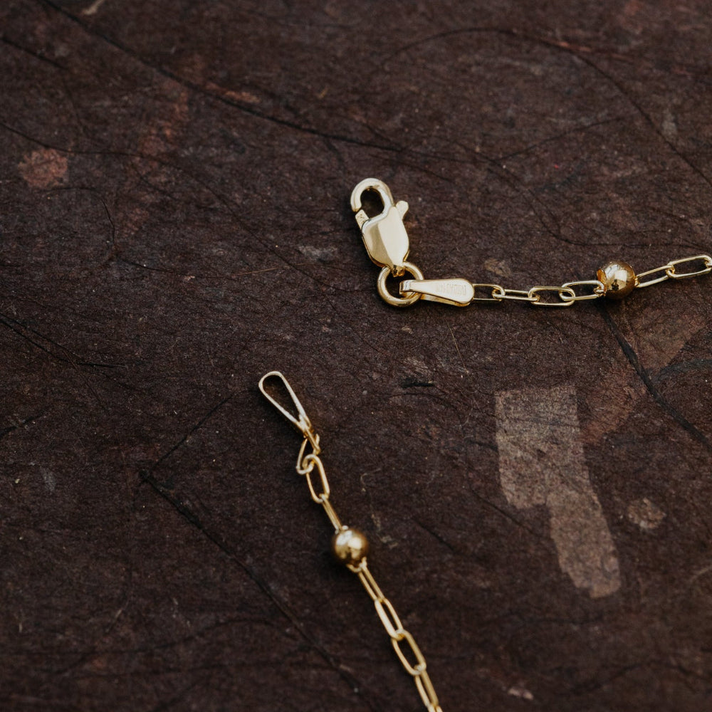 Gold bracelet with clasp on a dark textured surface