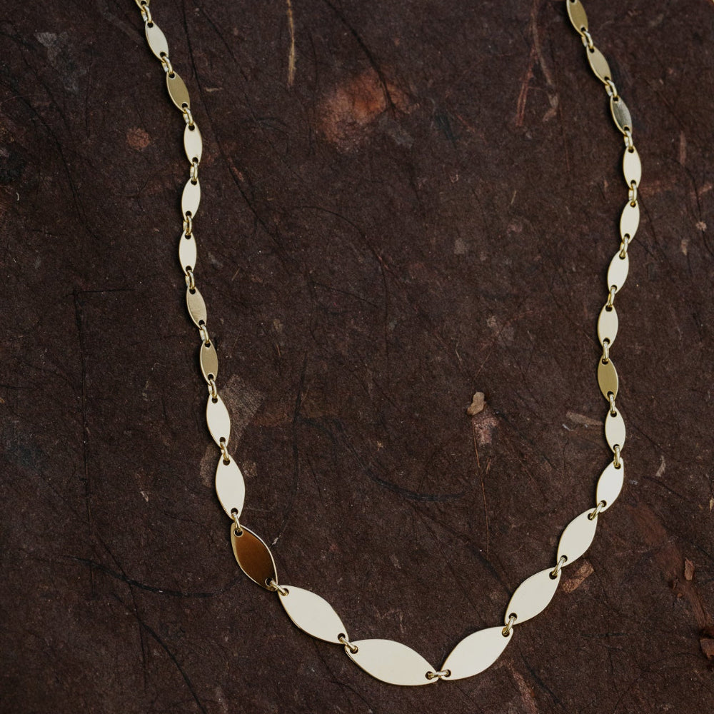 Gold and silver chain necklace on a dark textured surface