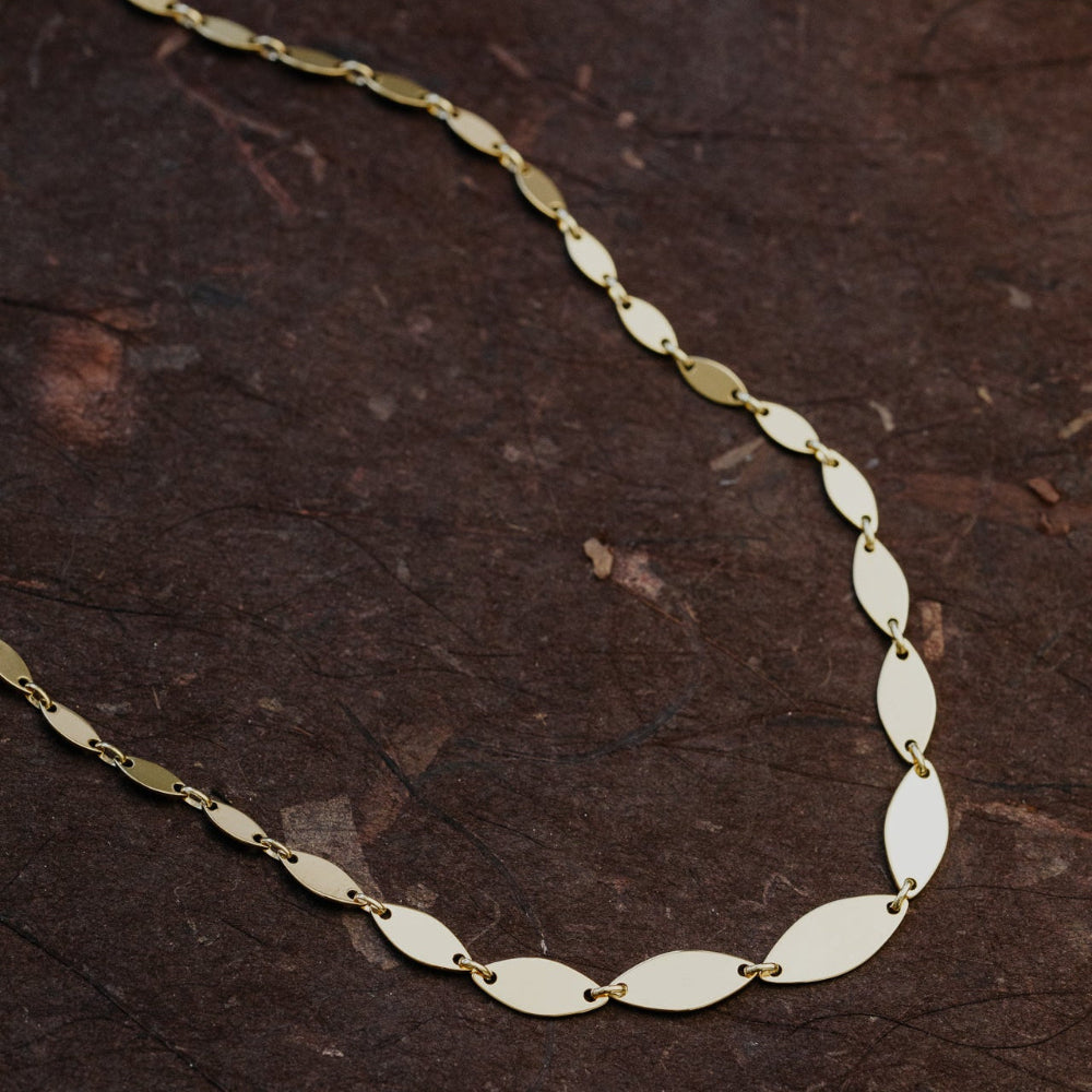 Gold chain necklace on a dark wooden surface