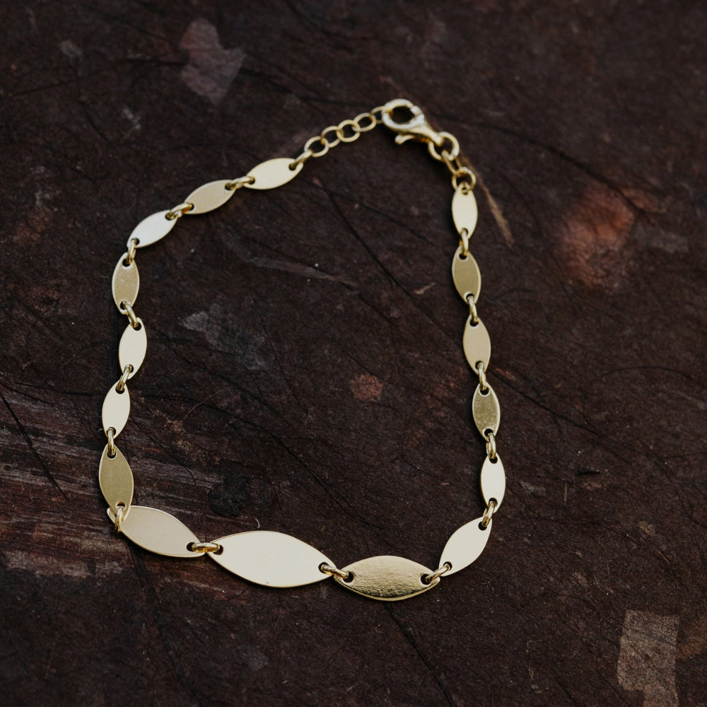Gold bracelet on a dark wooden surface