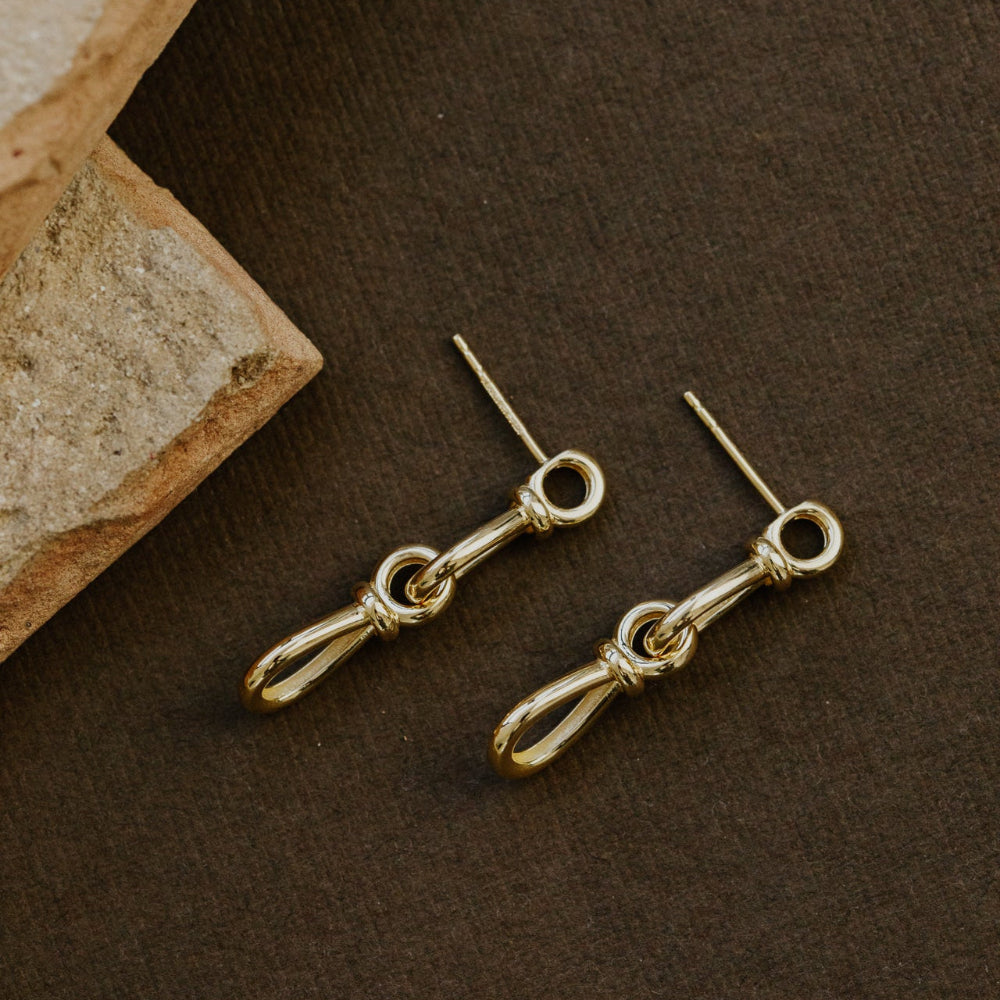 Gold earrings on a brown surface