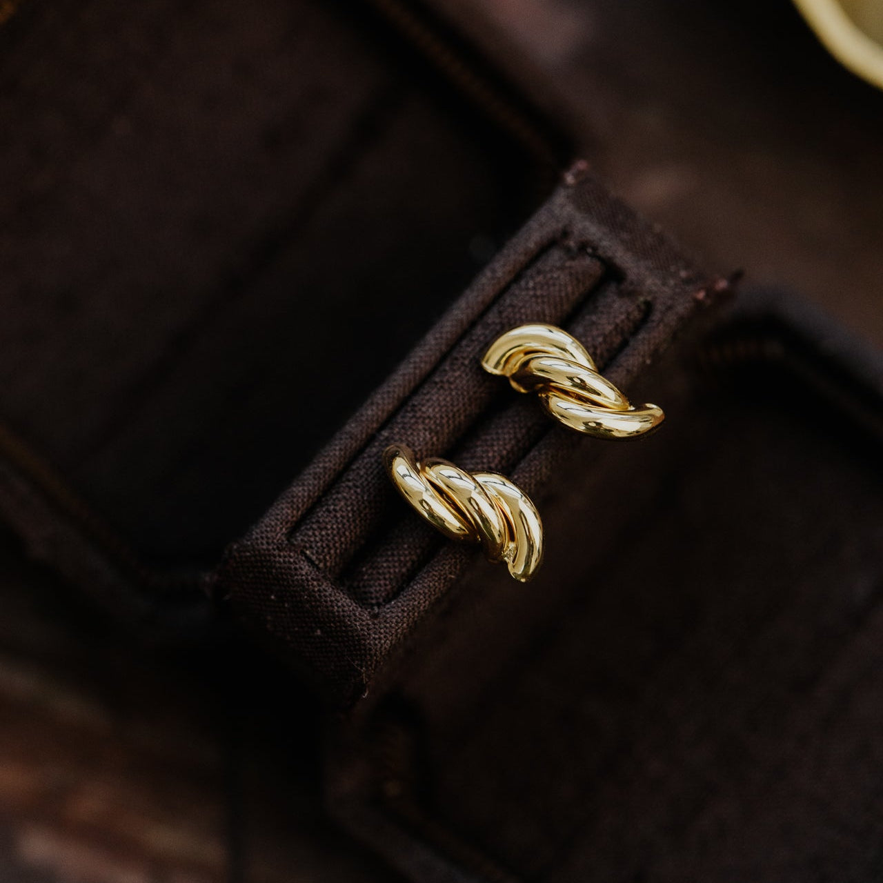 Gold earrings in a brown jewelry box