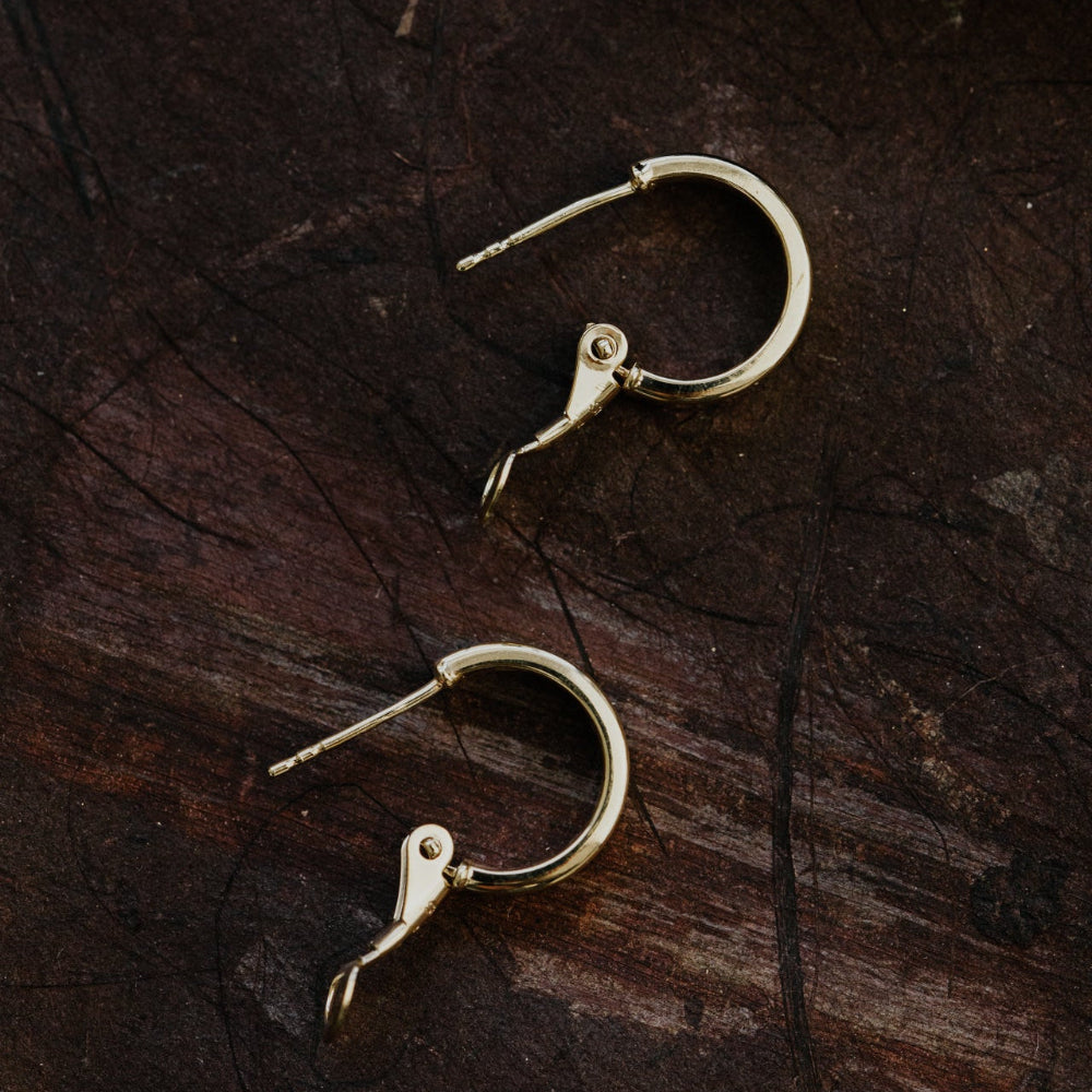 Gold hoop earrings on a dark wooden surface