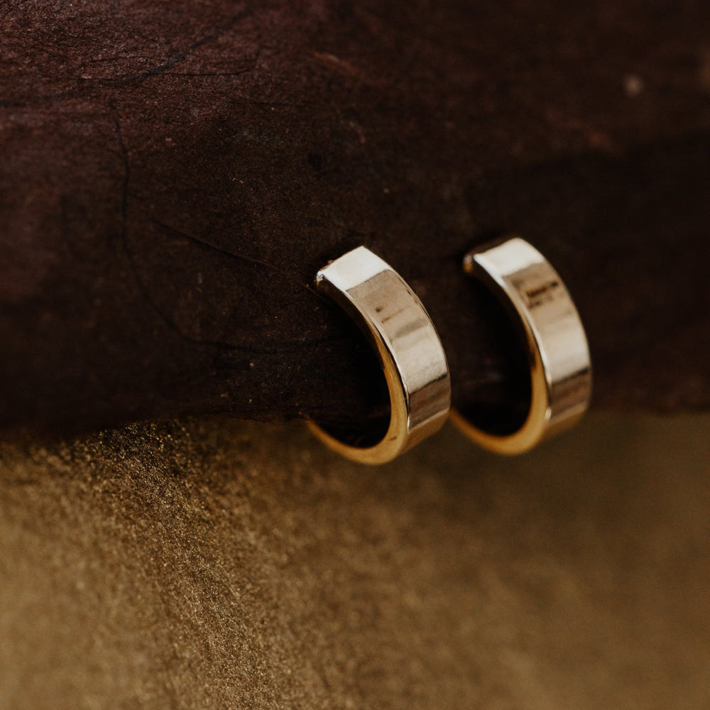 Gold hoop earrings on a brown textured surface